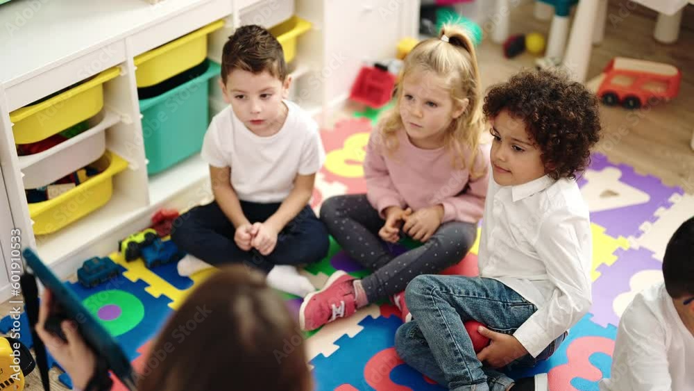 Poster Group of kids sitting on floor having lesson with touchpad at kindergarten