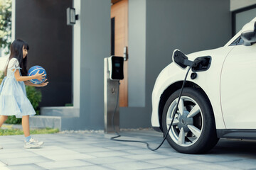 A playful and happy girl playing around at her home charging station providing a sustainable power...