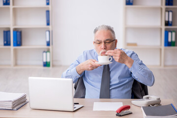 Fototapeta premium Old male employee drinking coffee during break