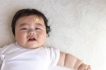 頬っぺたに絆創膏を貼った赤ちゃん（生後5か月、日本人、男の子）