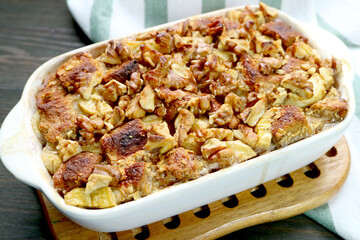 Bowl of Freshly Baked Delectable Banana Walnut Bread Pudding on a Wooden Breadboard