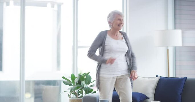 Funny, freedom and an old woman dance in the living room of her home during retirement. Party, music and dancing with a happy senior female pensioner laughing while feeling silly or crazy