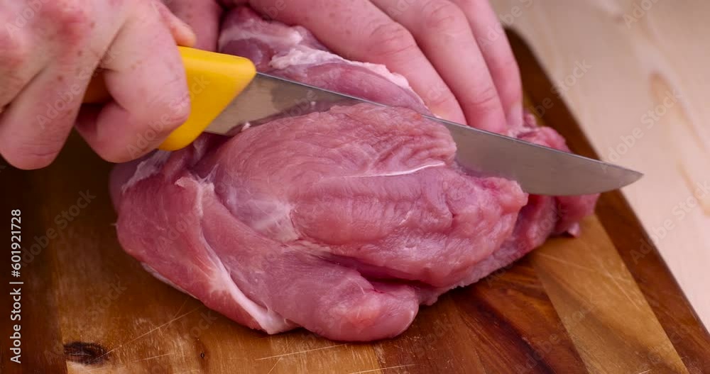 Wall mural Cut into pieces a piece of pork neck, a soft boneless part of pork while slicing for cooking