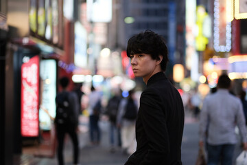 夜の繁華街を歩く若い男性