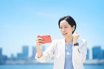 スマートフォンの画面を見ながら応援するビジネスウーマン