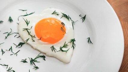 fried egg in the shape of a heart with dill. Romantic breakfas
