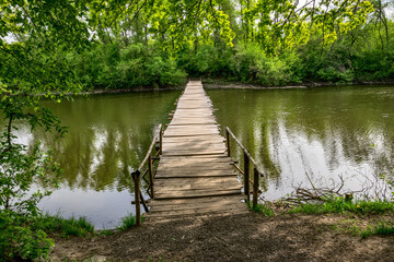 Wooden footbridge  across the river in a deciduous forest