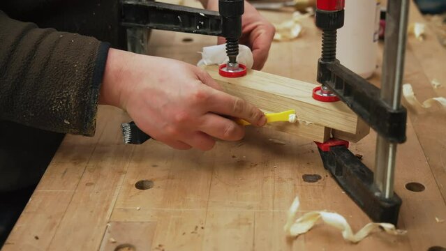 carpenter removing glue from the wooden piece, closeup shot, workshop. High quality 4k footage