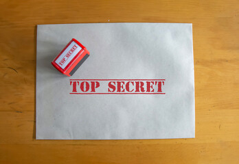 Top secret written straw paper envelope and stamp on desk. Secret goverment work or official paperwork concept idea. Top view. Free area for text. Selective focus