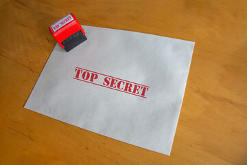 Top secret written straw paper envelope and stamp on desk. Secret goverment work or official paperwork concept idea. Free area for text. Selective focus