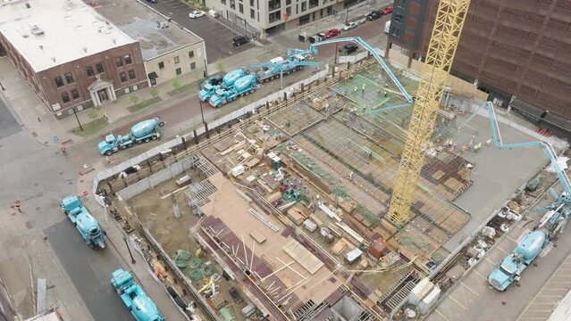 Aerial, concrete pump trucks pouring concrete on building foundation site