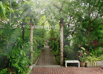 The path in the garden is paved with wormy bricks and the wooden entrance door with natural background in Thailand.