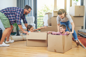 Child, happiness and boxes with family moving in apartment for fun and enjoyment on the floor. Parents, happy and children excited in a box at family home for investment and a lifestyle with love.
