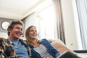 Fototapeta premium Laughing couple, relax and watching tv in home for funny movie, comedy show and media connection in lounge. Mature man, happy woman and smile for television, video subscription and streaming platform
