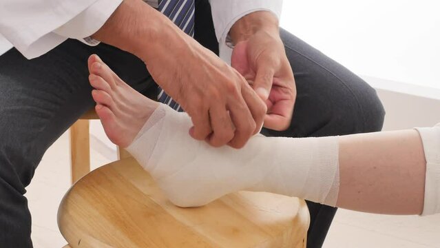 足首に包帯を巻く医者　顔無し