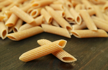 Closeup of Ridged Surface of Dried Penne Rigate Scattered on Wooden Table