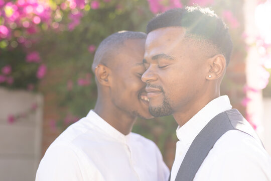 Closeup portrait of african american young man kissing boyfriend at wedding ceremony on sunny day
