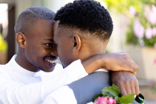 Closeup of newlywed african american gay couple with face to face embracing and posing at ceremony