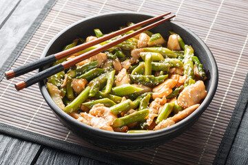 Fried chicken with asparagus and sesame close-up in a bowl on the table. Horizontal
