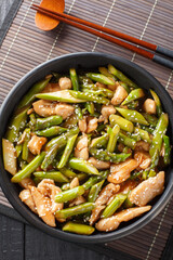 stir fry chicken with asparagus in spicy sauce close-up in a bowl on the table. Vertical top view from above