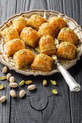 Baklava is a layered pastry dessert made of filo pastry, filled with chopped nuts and sweetened with syrup or honey closeup on the plate on the wooden table. Vertical