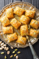 Baklava is a layered pastry dessert made of filo pastry, filled with chopped nuts and sweetened with syrup or honey closeup on the plate on the wooden table. Vertical top view from above