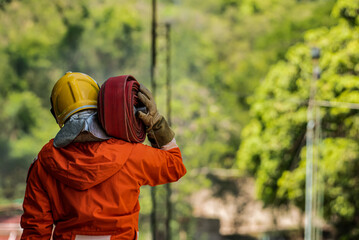 Firefighter's well defined muscles flexed as he effortlessly lifted the heavy water hose onto his shoulder ready to confront the relentless onslaught of the raging flames.