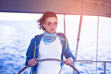 Woman standing behind the sailing wheel on a boat, sailing.