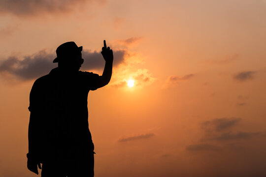 the silhouette image of a boy showing middle finger attitude image with sky in the background