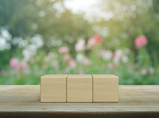 Three block cubes on wooden table over blur pink flower and tree in garden