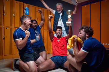 Group of young football players celebrating success in the locker room with their senior coach in...