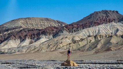 Man with scenic view of colourful multi hued Amargosa Chaos rock formations in Death Valley National Park, Furnace Creek, California, USA. Barren desert landscape of Artist Palette in Black mountains