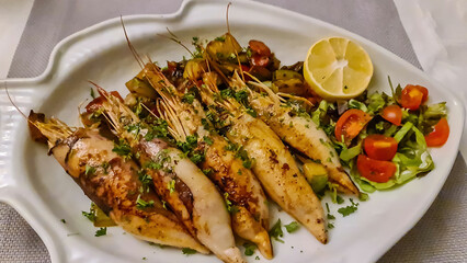 Plate of grilled squid with fresh lemon served in local restaurant in coastal village Sveti Stefan, Budva Riviera, Adriatic Mediterranean Sea, Montenegro, Europe. Local traditional sea food