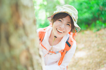 木陰から顔を出す登山を楽しむ笑顔の女性