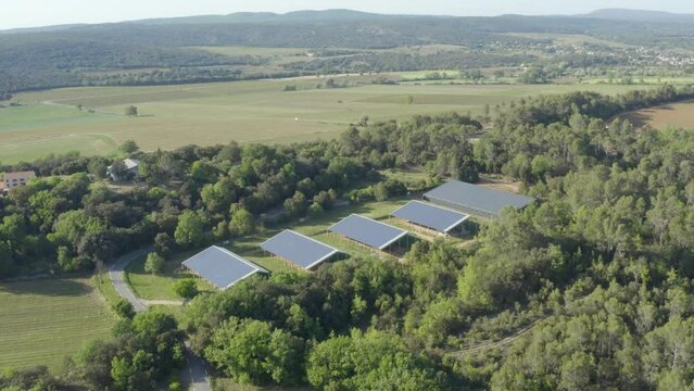 Aerial shot approaching a solar panel farm nestled in a forest in the countryside