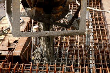 Construction worker pouring cement or concrete with pump tube at construction site