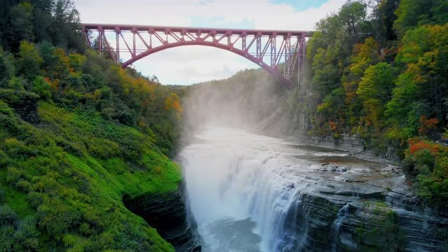 Aerial Pull Back at Upper Falls with Bridge in Letchworth State Park. Wide shot aerial drone shot pull back of the upper falls and bridge at Letchworth State Park
