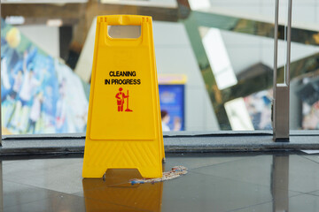 yellow cleaning in progress  sign floor on dirty floor. warning signboard on pathway in building.