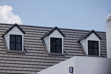 Garret's house with roof shingle.  flat roof tiles with blue sky.