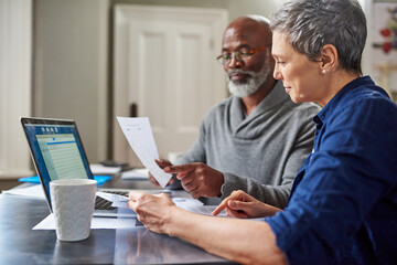 Laptop, documents and finance with a senior couple busy on a budget review in the home together....