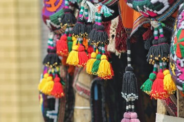 Fototapeta na wymiar Colored woolen goods in the Asian market. Fringe on pendants to scare away evil spirits from the house. National amulets of Central Asia.