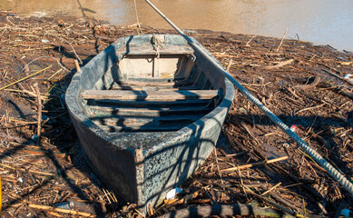 an ancient disused boat in the middle of a river flood with its debris