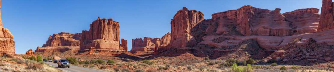 Cars with tourists drive along the road through Arches National Park admiring the diverse and unique forms of rocks, Utah, United States