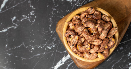 Cashew nuts . Roasted cashew nuts with shell in wooden bowl. Superfood. Vegetarian food concept. Healthy snacks. Top view. Copy space. Empty space for text