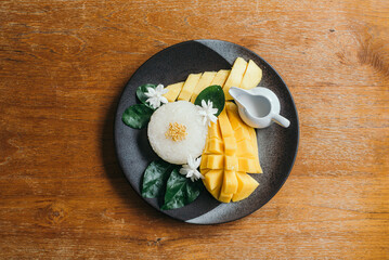 Mango with sticky rice dessert dish on cafe wooden table 