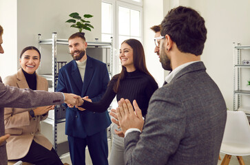 Team leader handshaking employee congratulating with professional achievement while colleagues supporting applauding. Businessman thanking for good project result. Career promotion, recognition