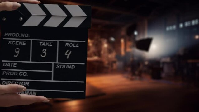 Human hands are using a clapperboard on set. Beginning of scene in film or TV television production. Concept of cinematography movie or video crew. Stage and filmmaking equipment background