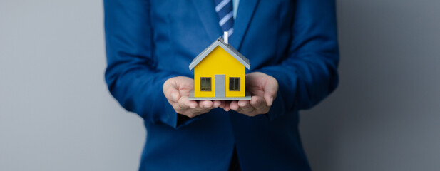 Person puts her hand on top of a miniature house model, photo of home insurance concept, when buying a new home should have home insurance to be sure if there is any danger to the home.