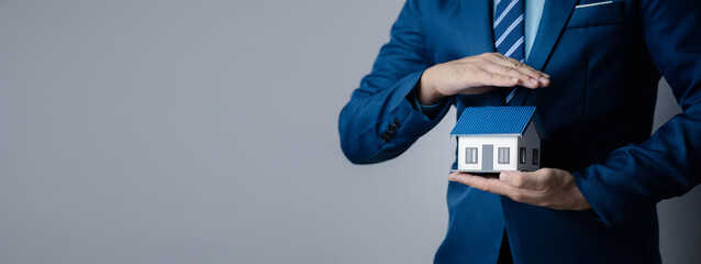 Person puts her hand on top of a miniature house model, photo of home insurance concept, when...