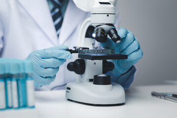 Lab assistant, medical scientist, chemistry researcher holds a glass tube through a chemical test tube, does a chemical experiment and examines a patient's sample. Medicine and research concept.
